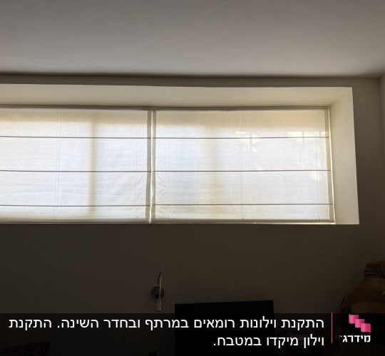 זוג וילונות רומאים בהירים להצללה מותקנים בחלון רחב